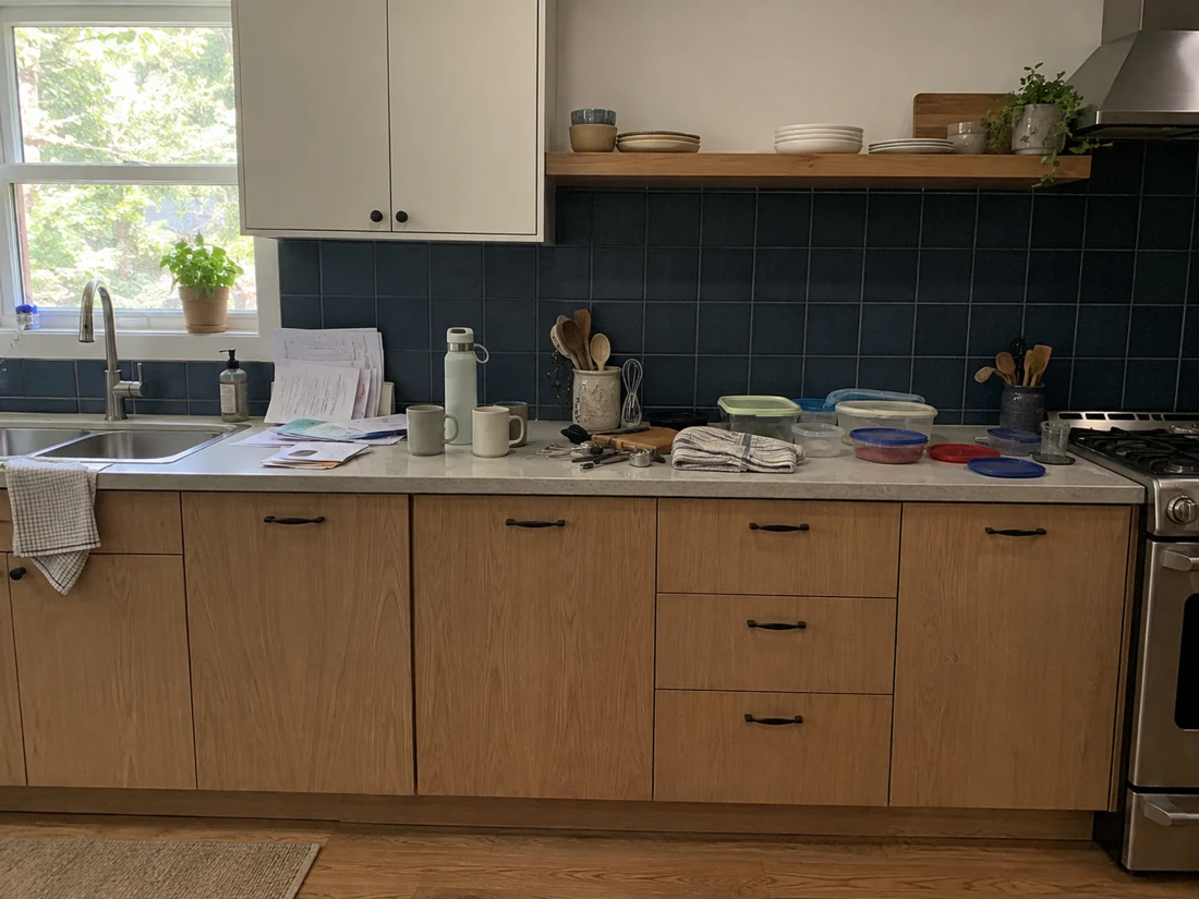 Original kitchen with loose containers, mail, and mugs on the counter